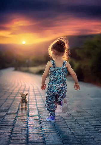 Toddler girl running with lion cub at sunset