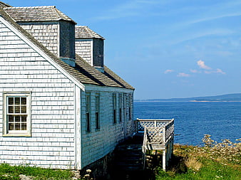 Weathered white coastal cottage overlooking the blue ocean