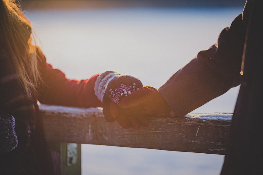 Couple Holding Hands in Winter Gloves at Sunset