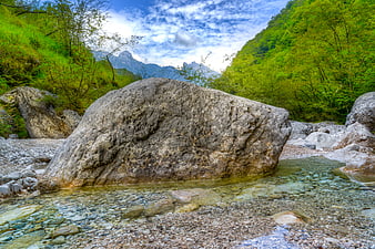 Large boulder in clear mountain stream with forest background