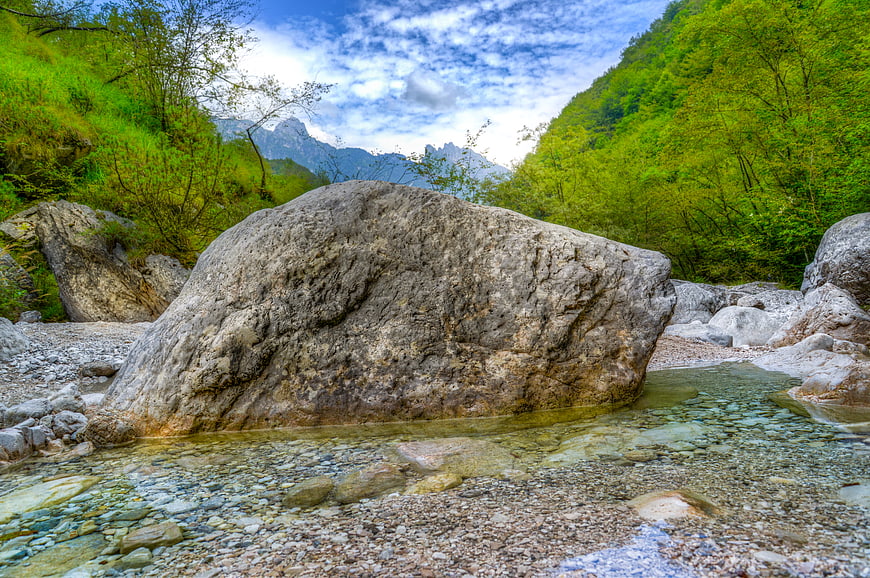 Large boulder in clear mountain stream with forest background