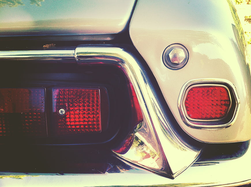 Close-up of vintage car taillight and chrome bumper