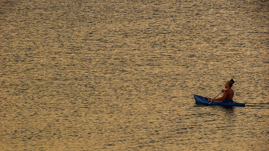 Man Kayaking on Golden Water at Sunset