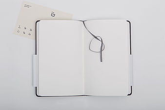 Open blank notebook with bookmark ribbon and card on white background