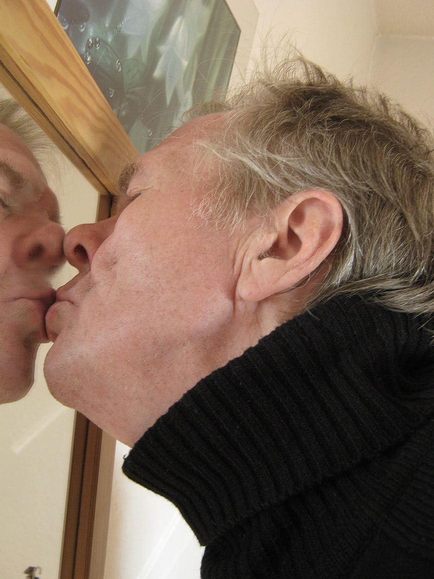 Senior man kissing his reflection in a mirror