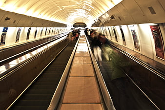 Motion blur commuters on subway escalator tunnel