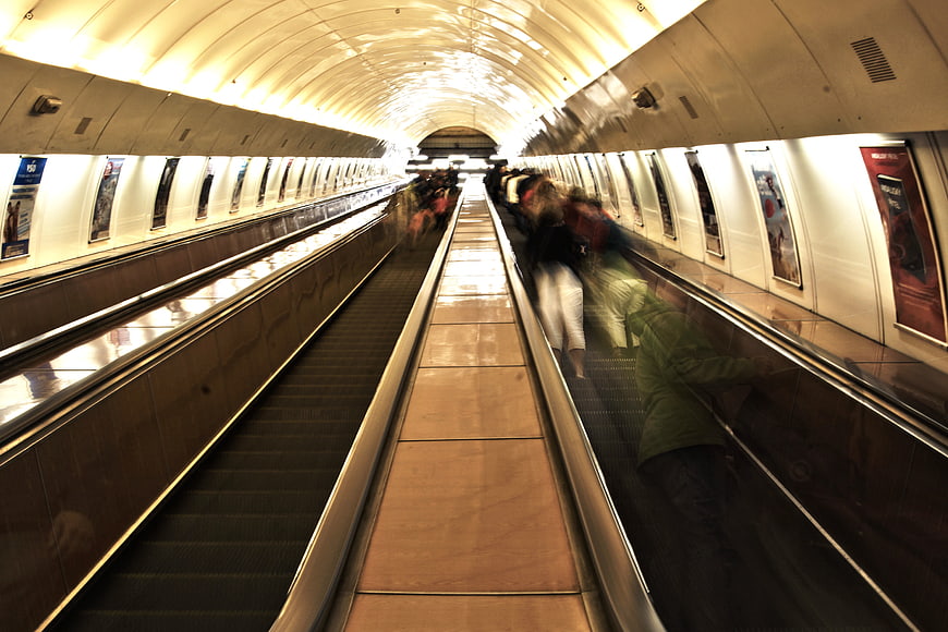 Motion blur commuters on subway escalator tunnel