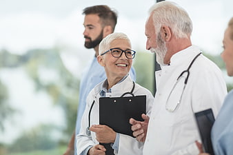 Senior doctors smiling and talking in hospital corridor