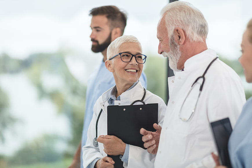 Senior doctors smiling and talking in hospital corridor