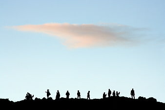 Silhouettes of people on a ridge against a blue sky