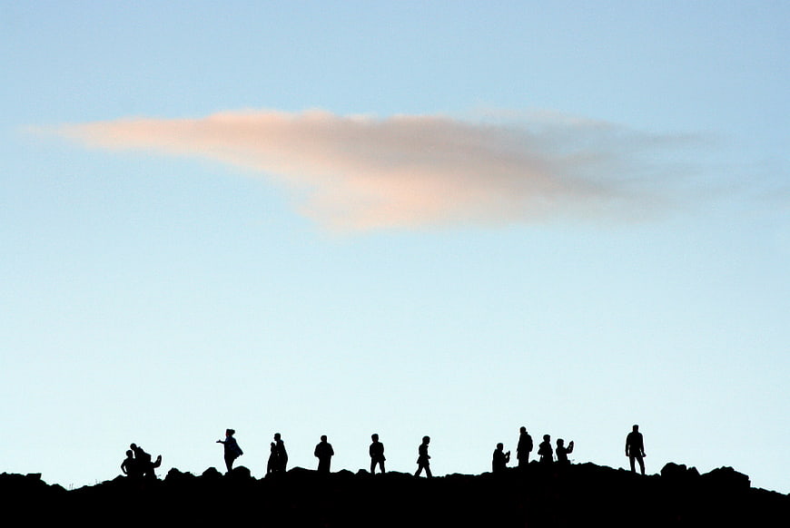 Silhouettes of people on a ridge against a blue sky