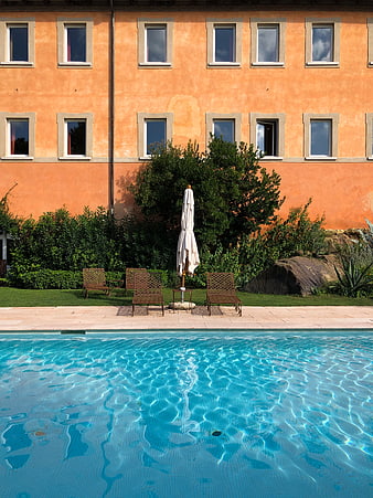 Serene swimming pool with terracotta hotel facade and lounge chairs