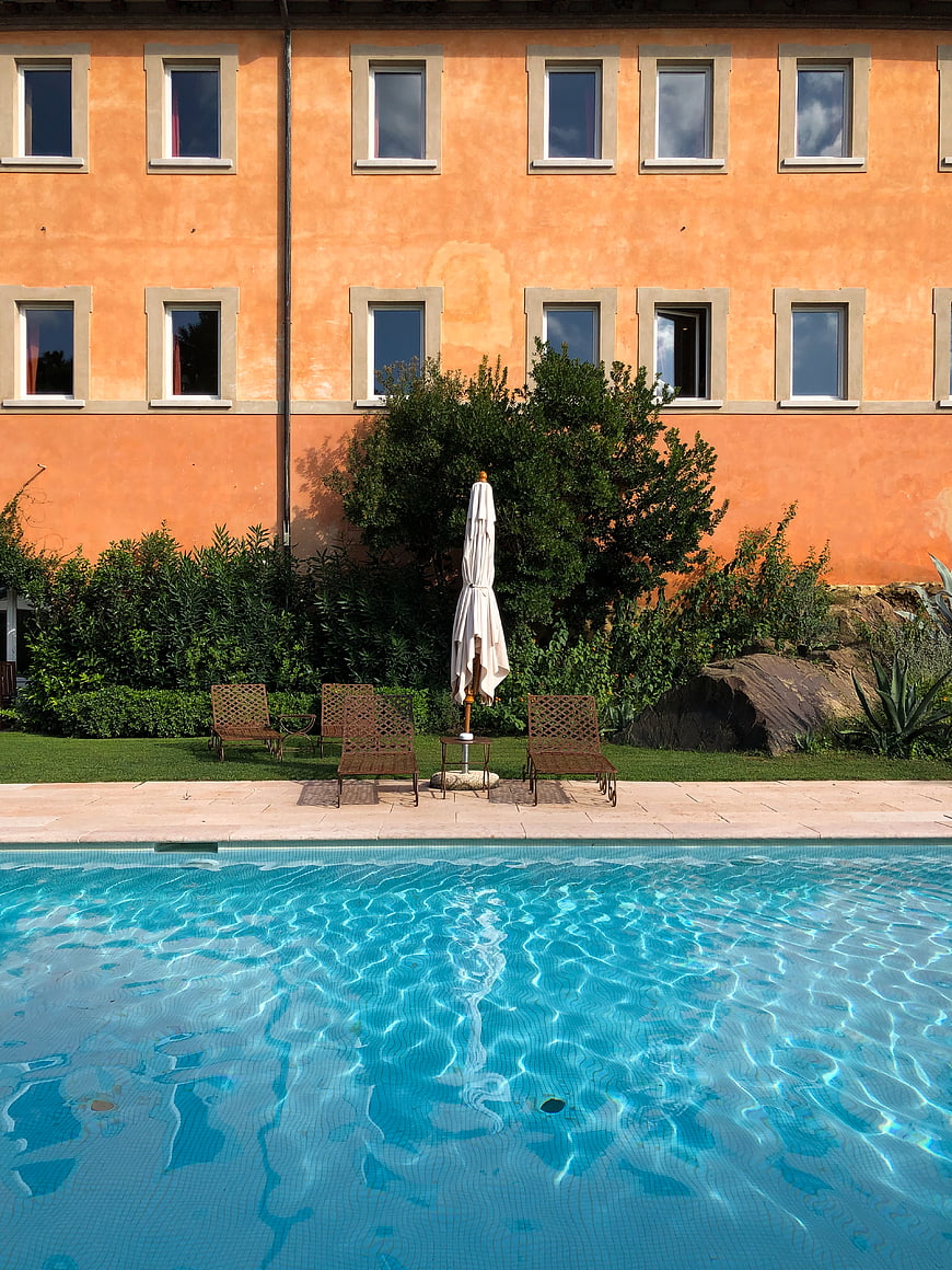 Serene swimming pool with terracotta hotel facade and lounge chairs