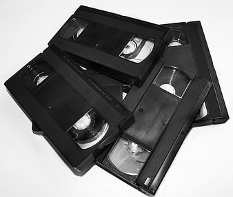 Black and white pile of vintage VHS cassettes on white background