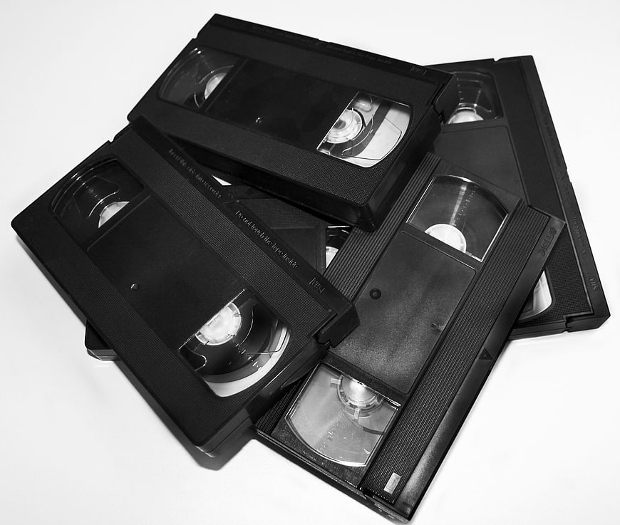 Black and white pile of vintage VHS cassettes on white background