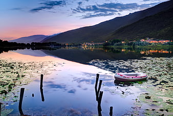 Inflatable boat on calm lake at sunset with mountains