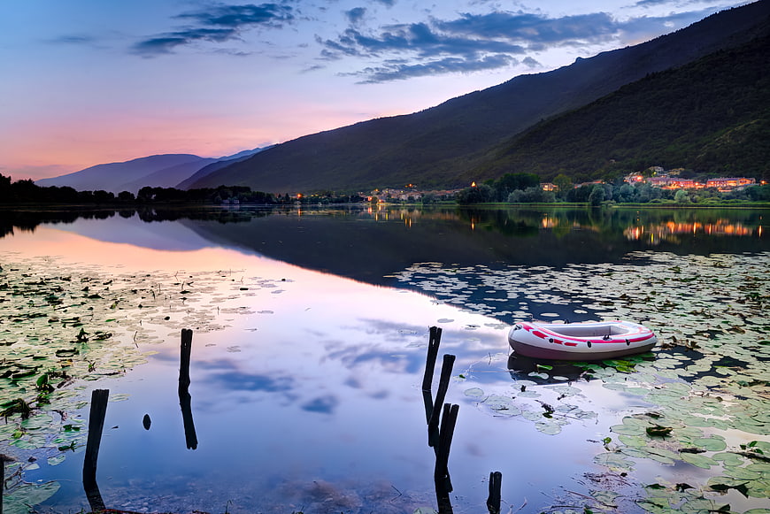 Inflatable boat on calm lake at sunset with mountains