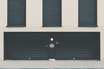 Minimalist modern building facade with black garage door and shutters