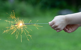 Child's Hand Holding Sparkler Outdoors