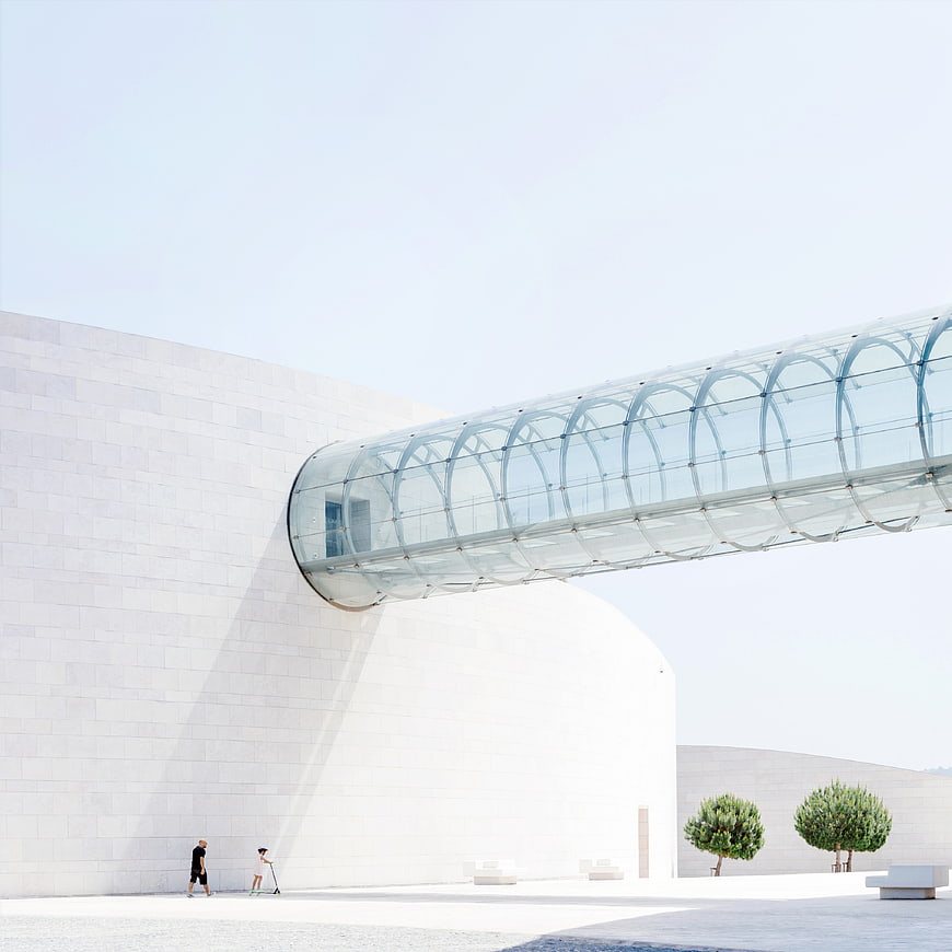 Modern white architecture with glass bridge and people