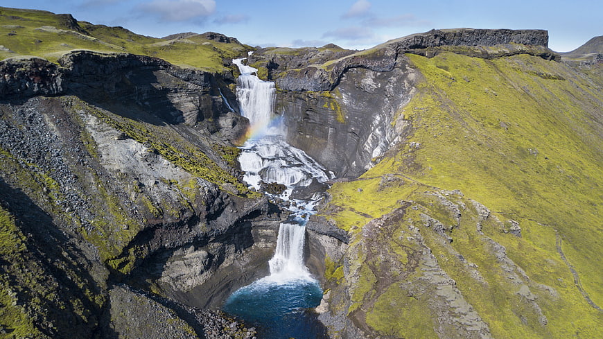 Aerial View of Majestic Waterfall in Green Icelandic Canyon