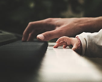 Adult and Child Hands Playing Piano Together