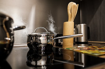 Steaming stainless steel pot on modern black glass stovetop