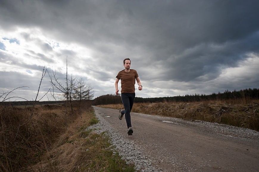 Man jogging on rural road under dramatic cloudy sky