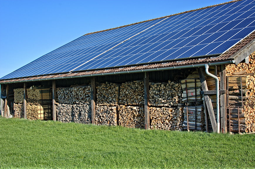 Solar panels on barn roof with stacked firewood