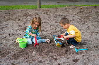 Young children playing with colorful toys in a backyard sandpit