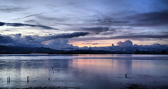 Serene Sunset Reflection Over Calm Water and Distant Mountains
