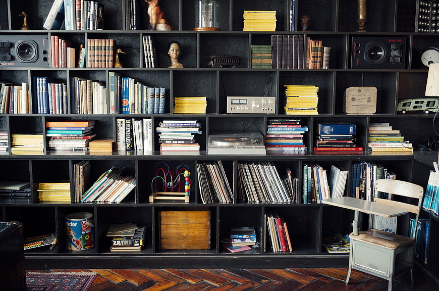 Vintage black bookshelf filled with books, vinyl records, and retro decor