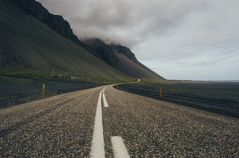 Empty Gravel Road Winding Through Dramatic Mountain Landscape