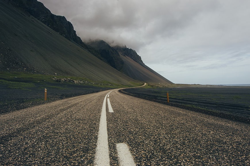 Empty Gravel Road Winding Through Dramatic Mountain Landscape