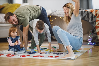 Happy family playing Twister game on living room floor