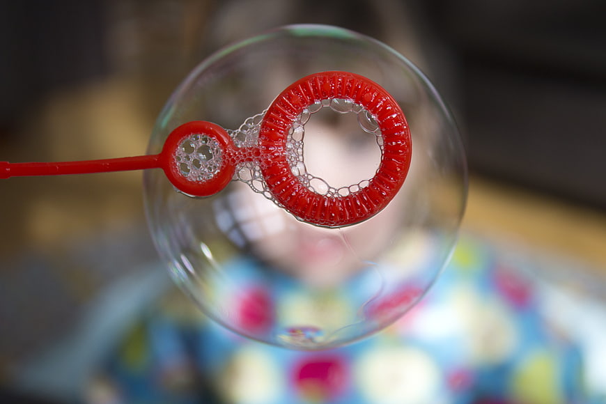 Close-up of red bubble wand creating a large soap bubble