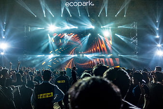 Vibrant concert crowd with dramatic blue stage lighting and beams