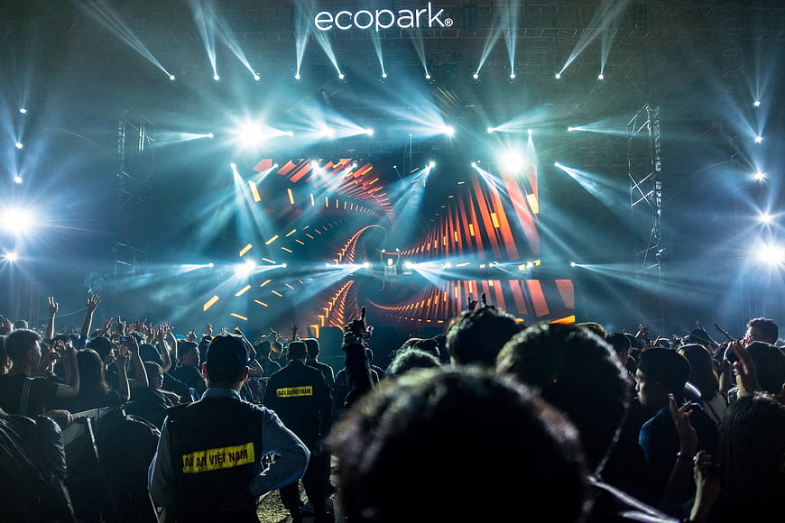 Vibrant concert crowd with dramatic blue stage lighting and beams