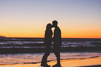 Silhouette of couple kissing on beach at sunset