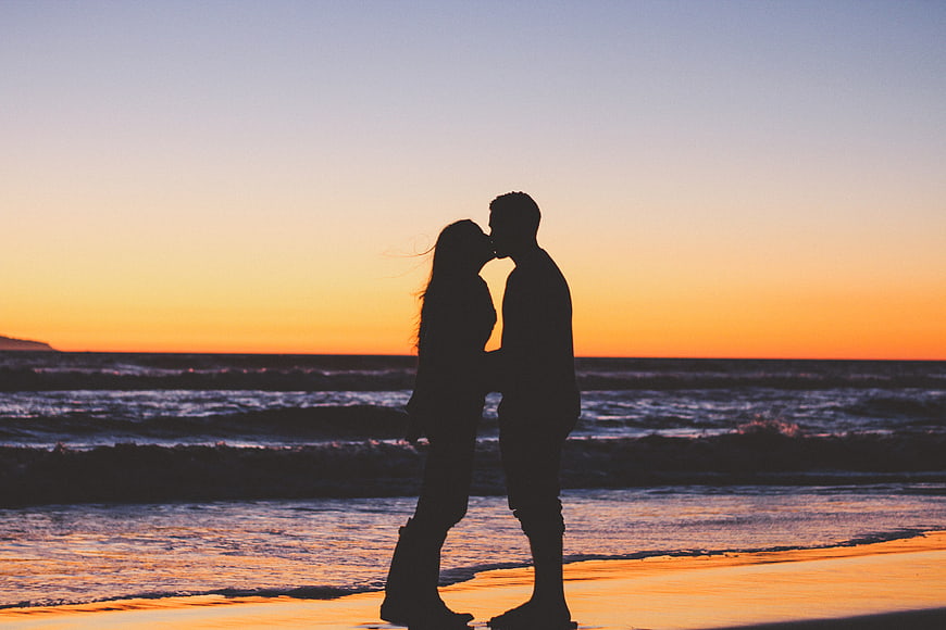 Silhouette of couple kissing on beach at sunset