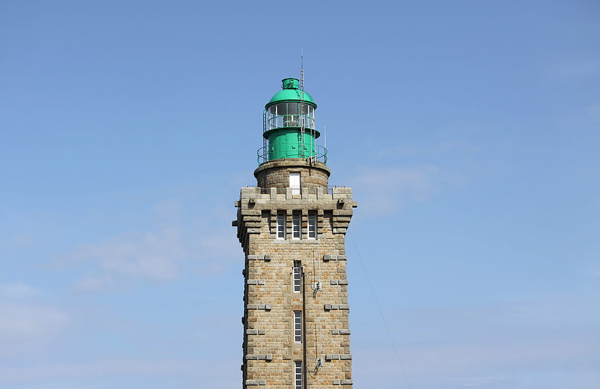 Stone Lighthouse Tower with Green Lantern Against Blue Sky
