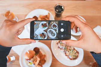 Hands taking photo of food with smartphone at restaurant
