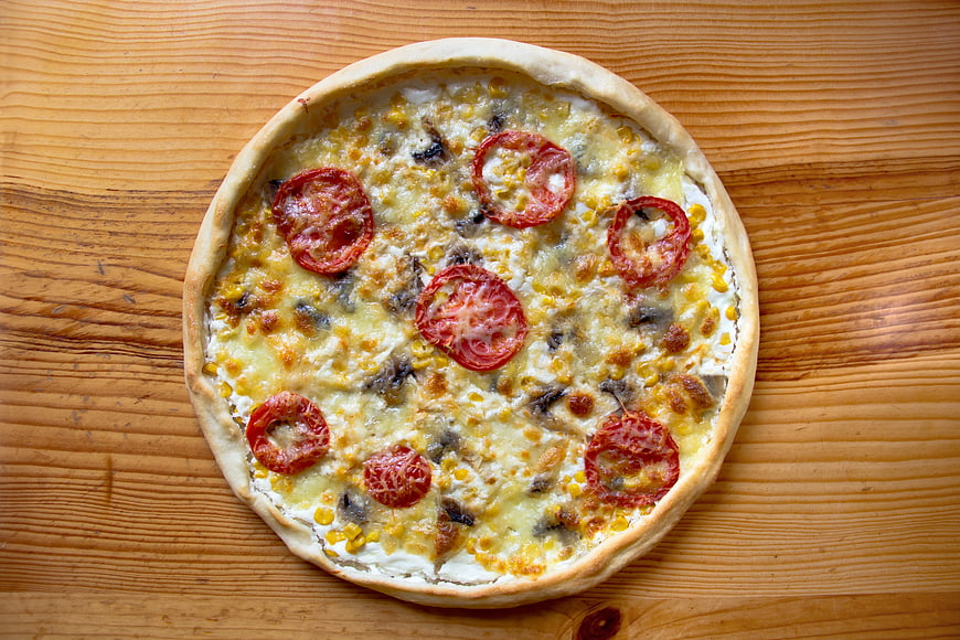 Homemade Pizza with Tomatoes and Corn on Wooden Table