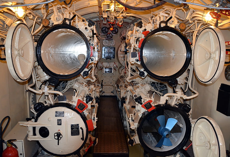 Interior of a submarine torpedo room with open hatches
