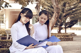 Two Vietnamese Students Studying Outdoors with Blue Folders