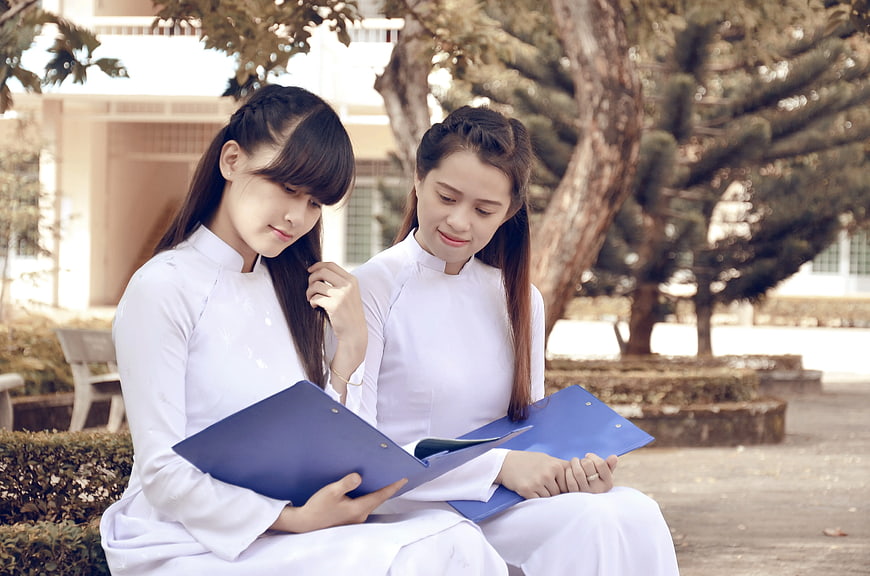 Two Vietnamese Students Studying Outdoors with Blue Folders