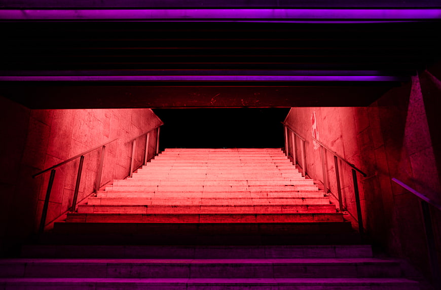 Neon illuminated concrete stairs at night with red and purple lights