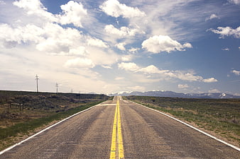 Straight Highway Stretching to Snow-Capped Mountains Under Blue Sky