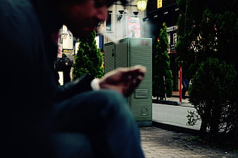 Man Smoking Cigarette on Urban Street at Night