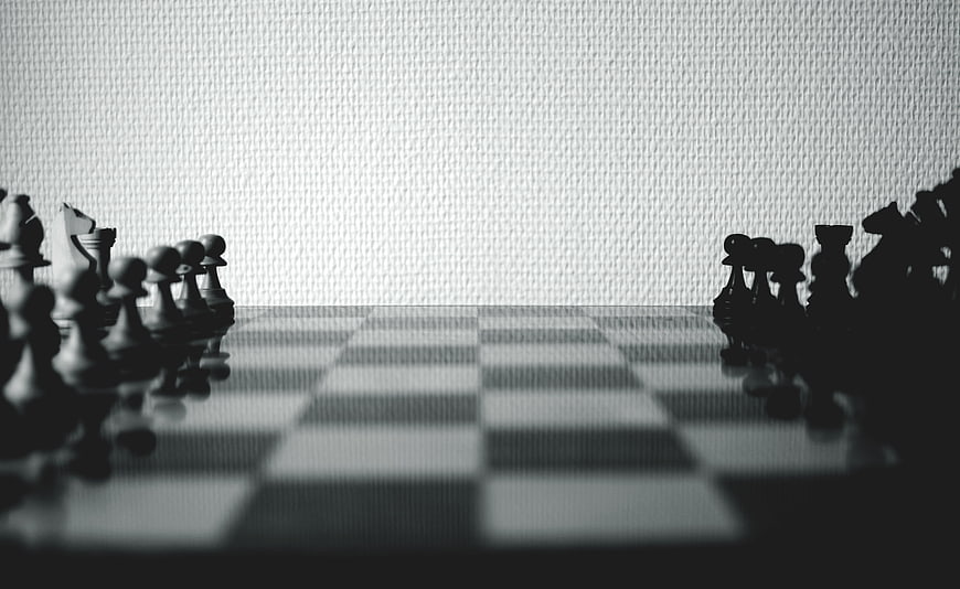 Black and white chess pieces on a board with blurred background